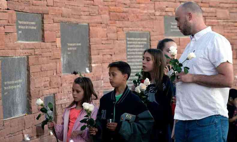 Sobreviventes de Columbine, familiares e amigos acenderam velas, rezaram e depositaram flores junto s placas com os nomes de seus entes queridos(foto: AFP / Jason Connolly )