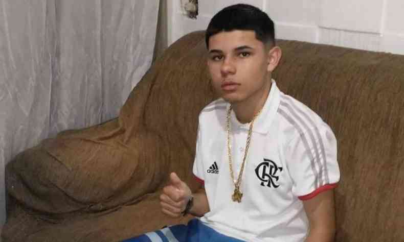 Jonathan Almeida Estellai, de 16 anos, em casa, sentado em um sof, olhando para a cmera. 