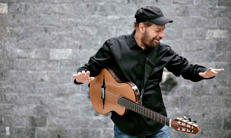 De camisa e bon� pretos, Jo�o Bosco com viol�o dependurado no pesco�o
