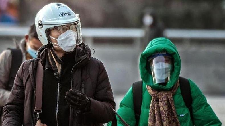 (foto: Reuters) Um homem usando capacete e máscara facial n95 caminha pelas ruas e uma mulher usando máscara e protetor facial atrás dele