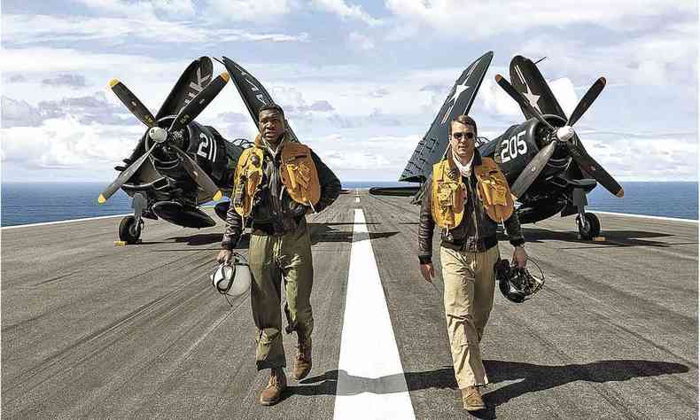 Os atores Jonathan Majors e Glen Powell caminham na pista de aeroporto  frente de avio em cena do filme 'Irmos de honra' 