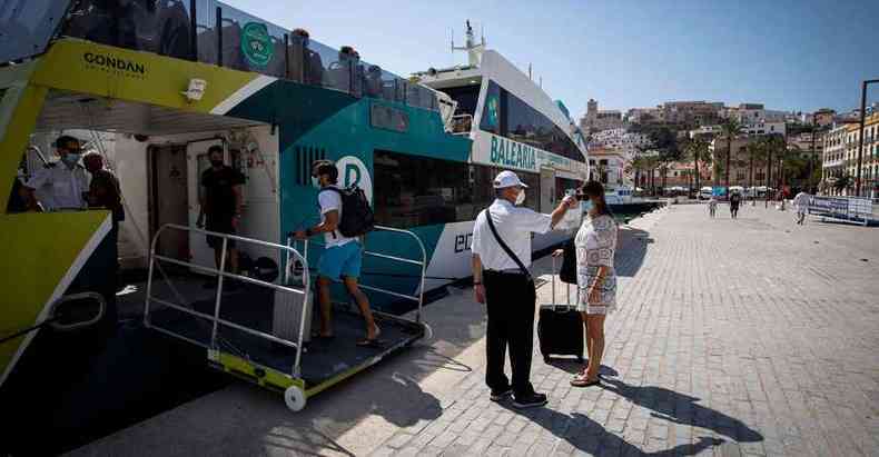 Em Ibiza, funcionrio mede temperatura de turista para entrada em embarcao: vrias regies espanholas tiveram reincidncia da doena(foto: JAIME REINA/AFP)