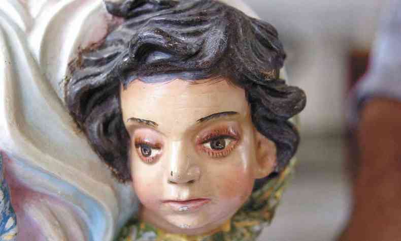Escultura de Nossa Senhora das Mercs com cabeleira vasta, olhos grandes e feio expressiva 