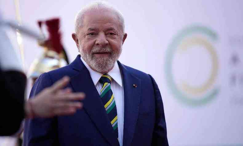 Presidente Lula. Ele  um homem branco de cabelos e barba branca. Usa um terno e uma gravata listrada