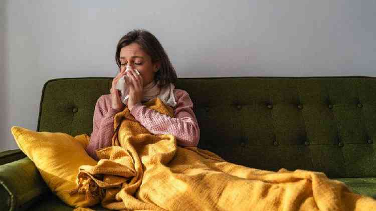 Mulher na cama com sintomas de resfriado