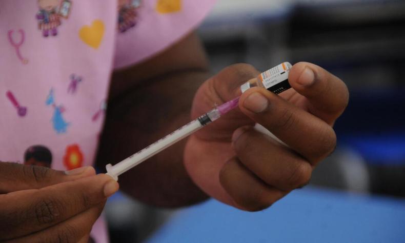 Após remessa de novo lote enviada pela SES-MG, a vacinação dessa faixa etária será retomada na capital (foto: Juarez Rodrigues/EM/D.A Press) Profissional de saúde prepara a vacina para aplicação