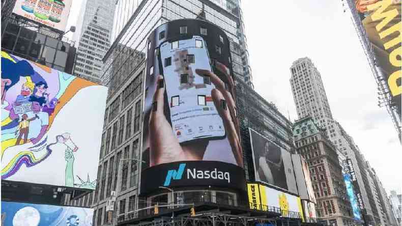 Fotografia colorida mostra um outdoor em Nova York com uma imagem do aplicativo da Nasdaq
