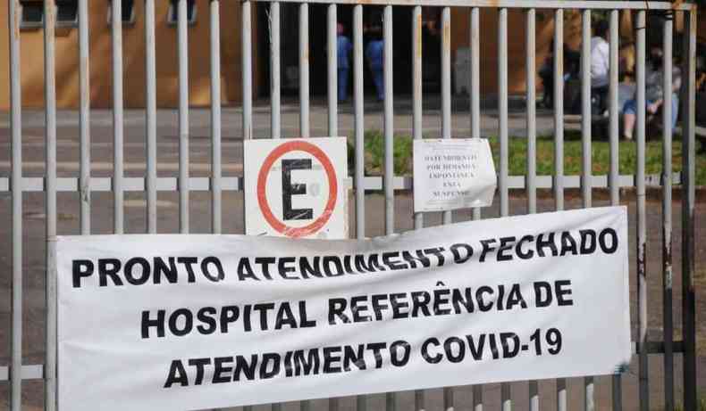 Grade do hospital fechada com uma faixa escrito 'Pronto atendimento fechado Hospital referncia de atendimento covid'