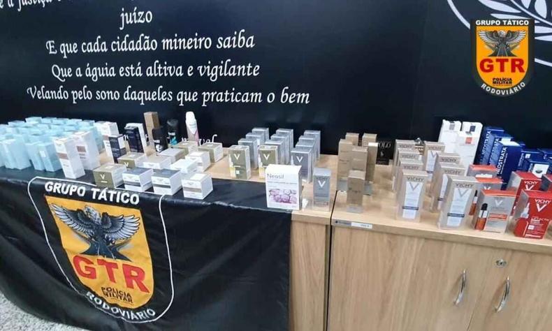 Uma enorme quantidade de produtos dermocosmticos em cima de mveis com o smbolo da polcia militar de Minas Gerais ao fundo.