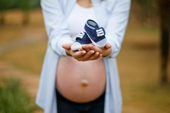 Do ponto de vista biológico, é ideal que a mulher engravide até os 35 anos(foto: Pixabay) Mulher grávida com o sapatinho do bebê nas mãos