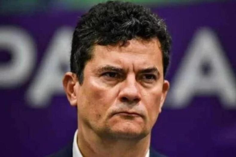 Srgio Moro com feio sria na frente de um painel azul escuro