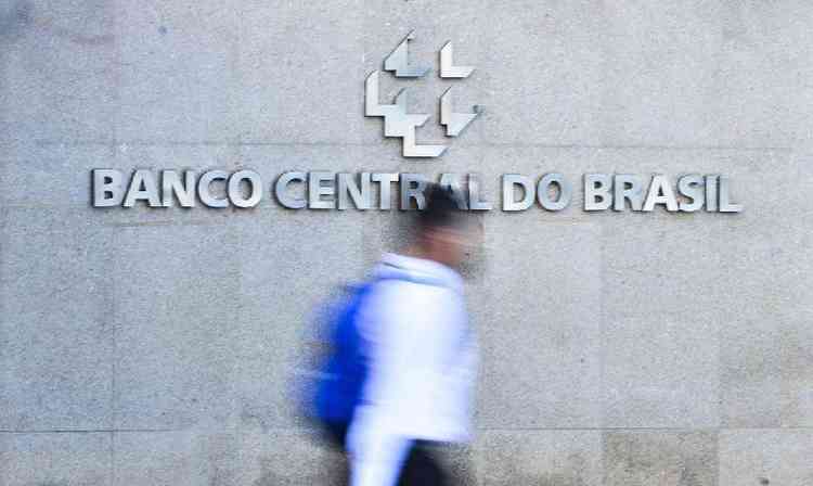 Silhueta de homem passando em frente ao logotipo do Banco Central do Brasil