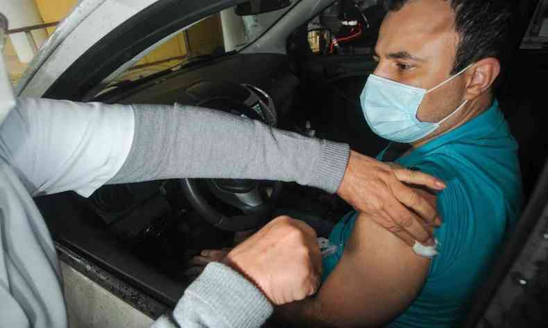Enfermeira aplicando vacina no brao do motorista de ambulncia