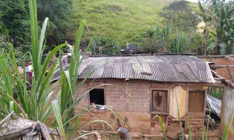Casa de barro com alguns tijolos coberta por lona 