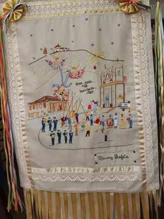 Estandarte de artess de Caet traz bordado colorido de cena da cidade e franjas de fitas