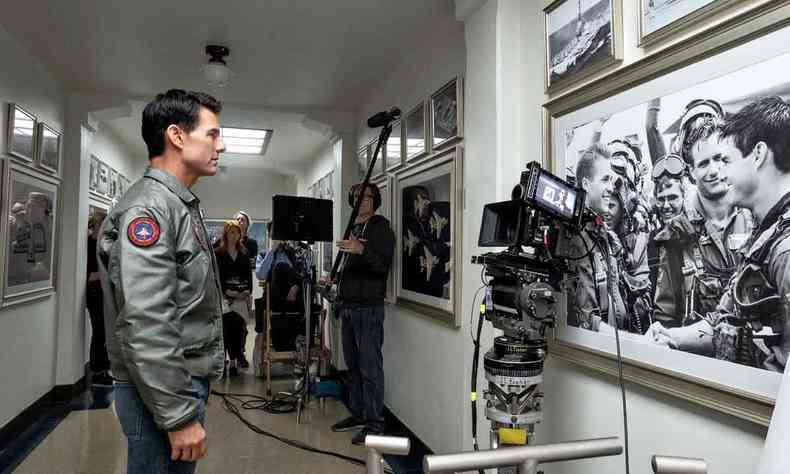 Tom Cruise grava cena de 'Top gun: Maverick' na qual seu personagem, de pé num corredor, observa foto dele mesmo em cena do filme anterior, 'Top Gun: Ases indomáveis'