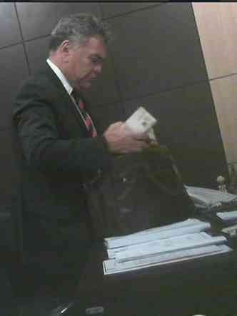 O ex-deputado estadual Hermnio Barreto coloca o dinheiro em uma mala(foto: Reproduo)