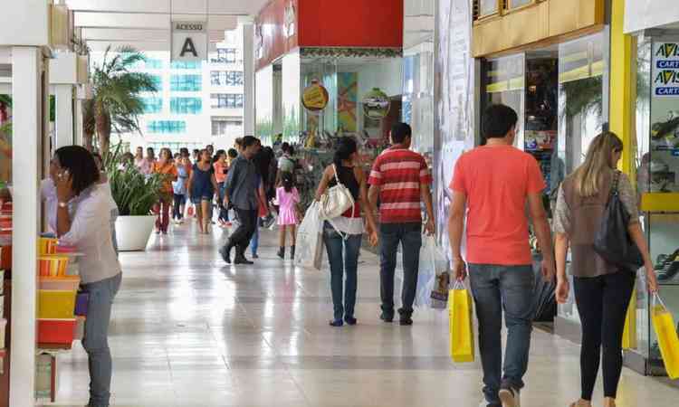 Vista de um ptio de um shopping com pessoas caminhando e carregando sacolas de compra