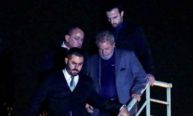 Cercado por agentes da Polícia Federal, o petista desembargou na noite de sábado em Curitiba, onde está preso(foto: / AFP / Heuler Andrey ) Cercado por agentes da Polícia Federal, o petista desembargou na noite de sábado em Curitiba, onde está preso(foto: / AFP / Heuler Andrey )