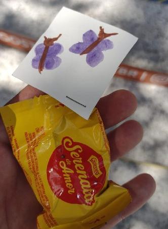 Mo segurando um bombom Serenata de Amor com um bilhete com duas borboletas pintadas 
