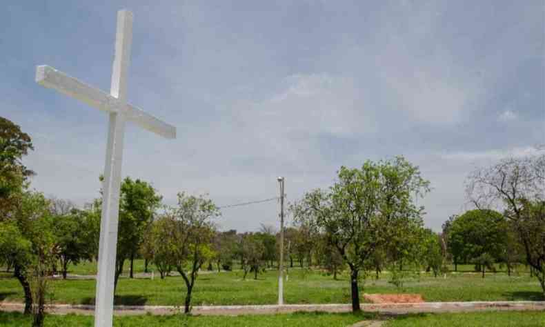 Cruz no cemitério da paz em Belo Horizonte, com paisagem de árvores ao fundo