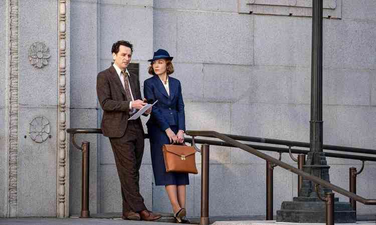 Atores Matthew Rhys e Juliet Rylance esto lado a lado, com figurinos dos anos 30, recostados ao corre-mo em frente a edifcio pblico, em cena da srie `Perry Mason 