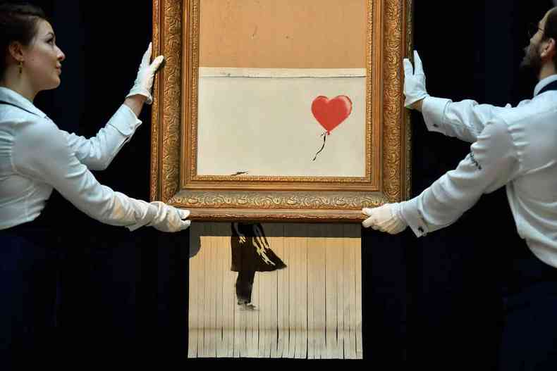 Funcionrios da Sotheby%u2019s de Londres retiram o quadro Girl with balloon, arrematado por R$ 4,9 milhes, em outubro passado. O artista britnico havia instalado um picotador na moldura, acionado logo aps a venda (foto: Ben STANSALL/AFP)
