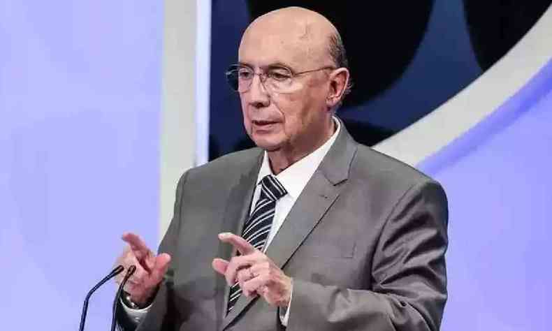 Henrique Meirelles com um terno falando ao microfone