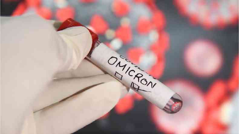 Mão com luva segura ampola com etiqueta escrito ômicron