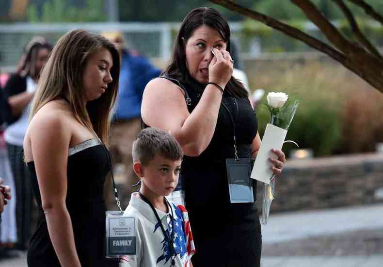 Mulher, com filhos, enxuga lgrimas durante homenagem aos que morreram no atentado das torres gmeas