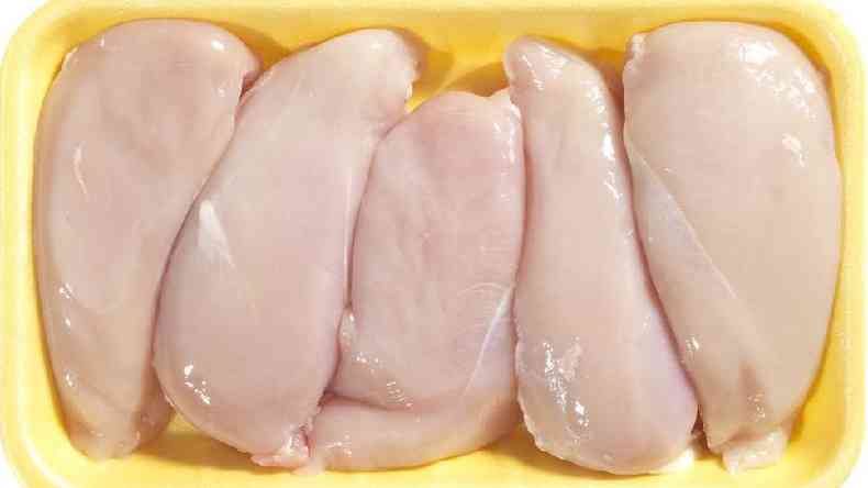 Peitos de frango sem a pele dispostos lado a lado numa bandeja amarela