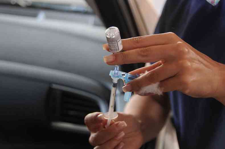 Enfermeira prepara vacina na seringa