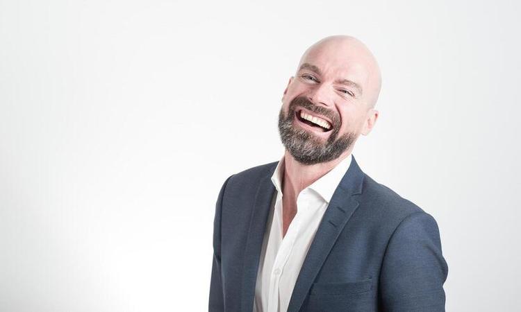 homem careca sorrindo, de barba e terno