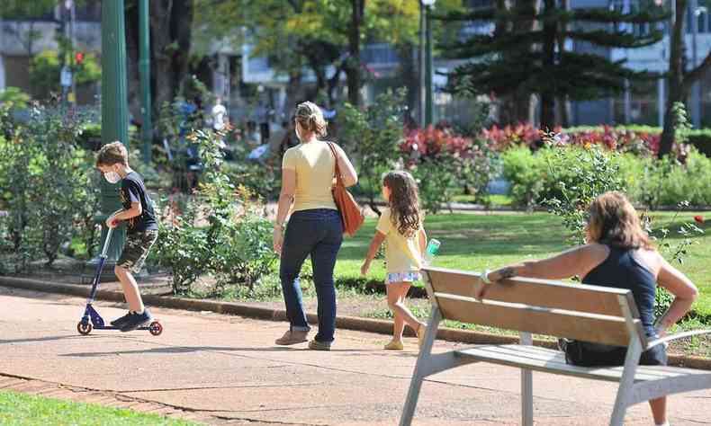 Adultos e crianças caminham em praça pública