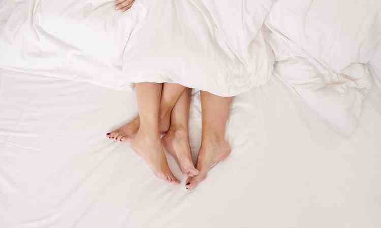 Duas pessoas com pés entrelaçados na cama
