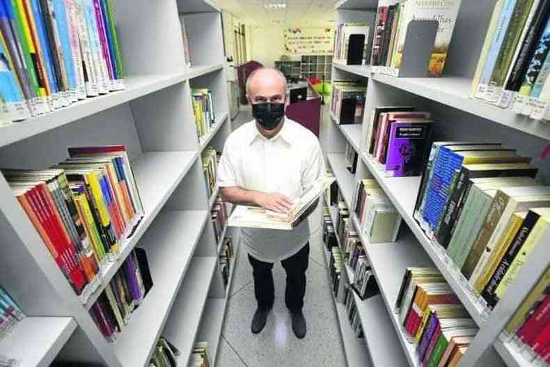 Homem segura livro em biblioteca