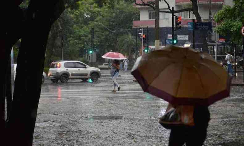 Chuva em BH; pessoas andam nas ruas de sombrinha