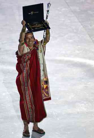 Um peruano vestido com trajes tradicionais segura a placa e o pergaminho