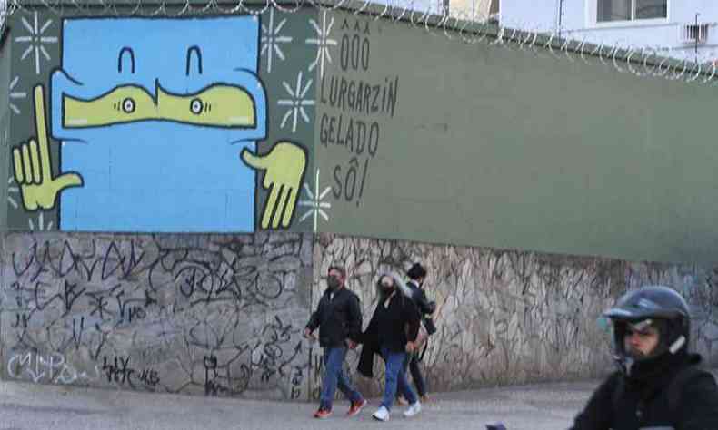 Pedestres agasalhados em Belo Horizonte. Grafite em muro na esquina da Rua Bernardo Guimares com a Avenida Afonso Pena acaba fazendo brincadeira com o clima na capital: 