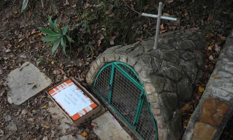 Cachorro morto colocado em caixa em praa do bairro Grajau. Caixa com co morto colocada ao lado de santurio de praa. Uma mensagem, com a data da morte do co, apela para coleta da caixa pela SLU