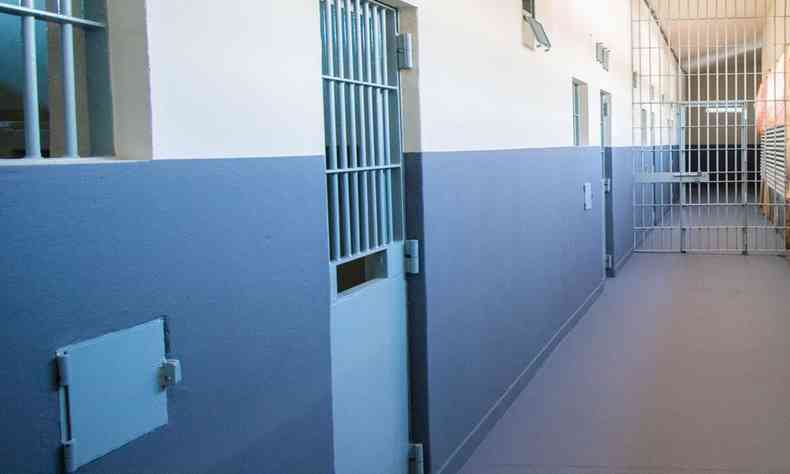 Corredor dentro de presdio mostrando portas das celas fechadas