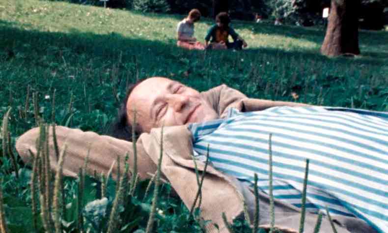 Deitado na grama, o cineasta Jonas Mekas sorri em cena de 'As I was moving ahead occasionally I saw brief glimpses of beauty'
