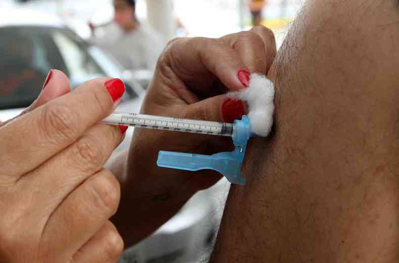 Enfermeira com seringa contendo a vacina Pfizer aplica nos pacientes