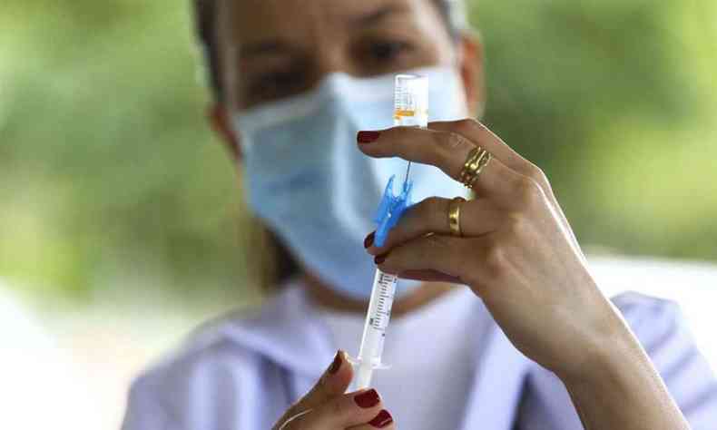 Mulher segurando seringa de vacina