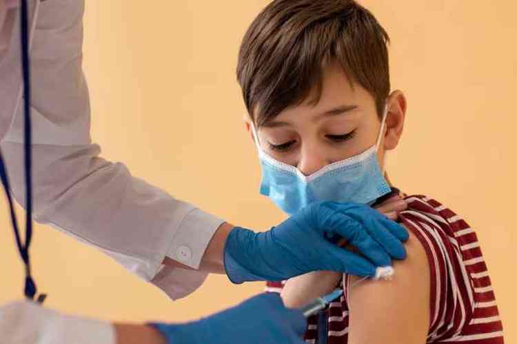 Menino de mscara recebendo vacina