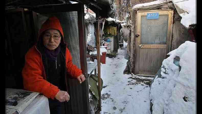 Um idoso sul-coreano sentado na comunidade de Guryong em Seul com neve no cho