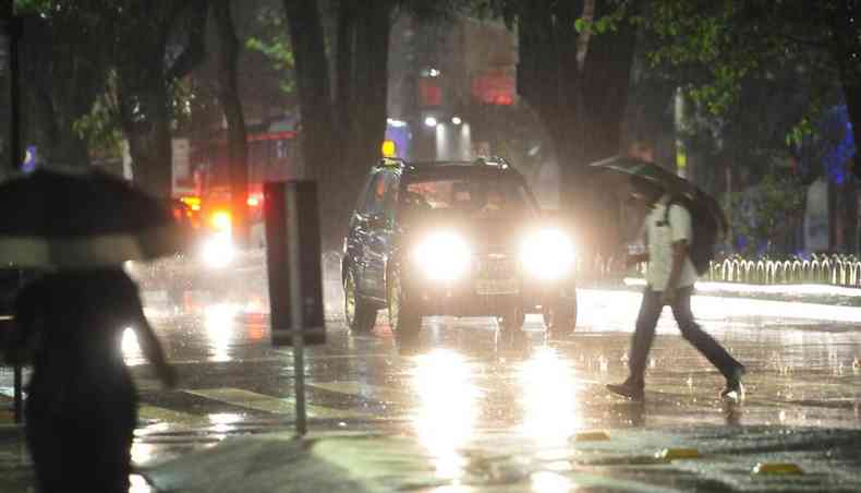Carro e pedestre sob chuva em BH 