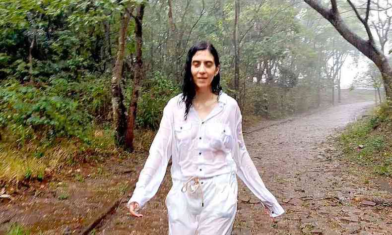 Atriz Camila Mota anda sob a chuva, numa estrada, em cena do documentário Lavra 