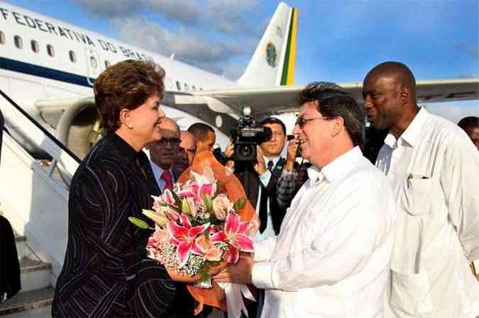 A presidenta Dilma Rousseff recebe flores do ministro das Relaes Exteriores cubano, Bruno Rodrgues Parrilla, ao desembarcar em Havana(foto: Roberto Stuckert Filho/Presidncia da Repblica)