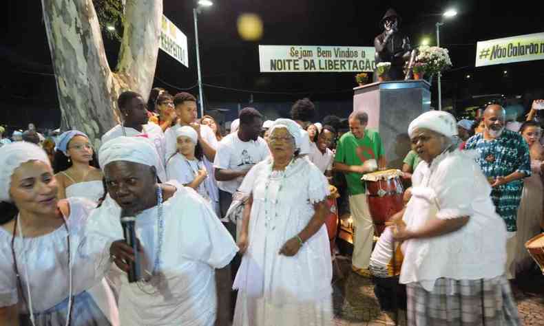 Mulheres negras com roupas tradicionais da umbanda catam ao microfone na Noite da Libertao na Praa 13 de maio, aos ps do busto do Preto velho